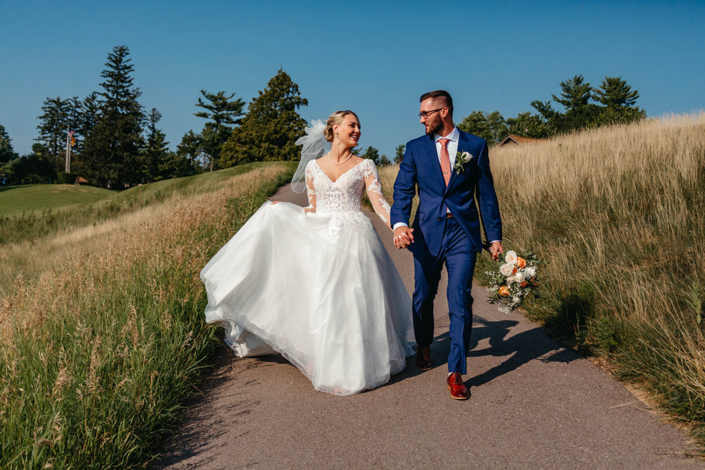 Couple walking through field in wedding dress.