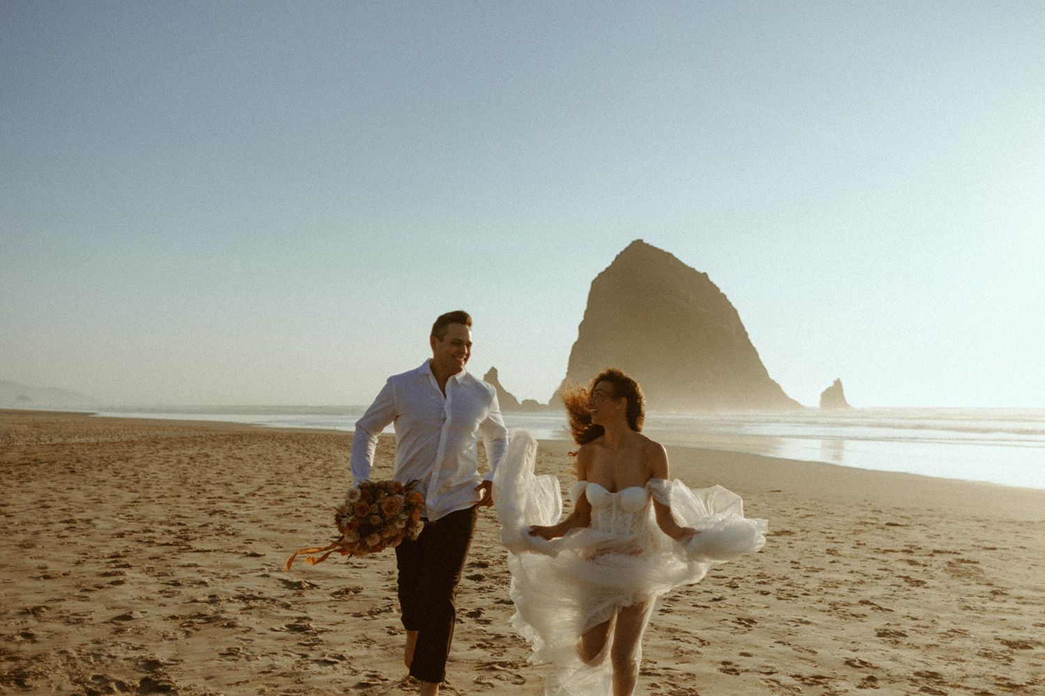 couple running on the beach during their cannon beach bridal session