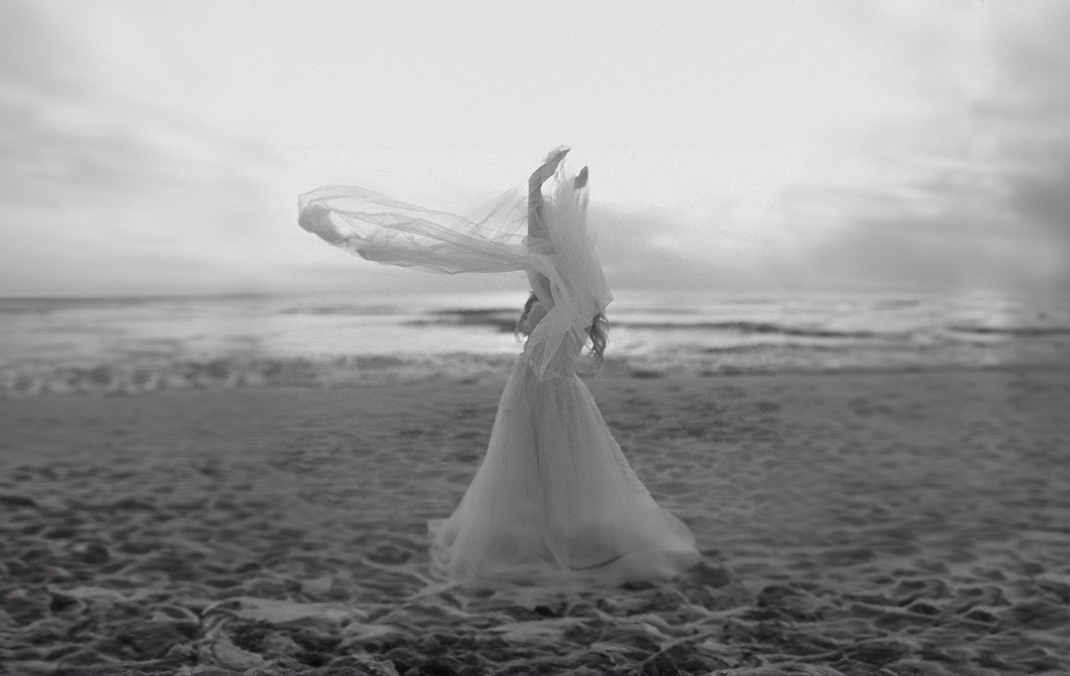 bride holding her veil in the wind during bridal photos on the beach